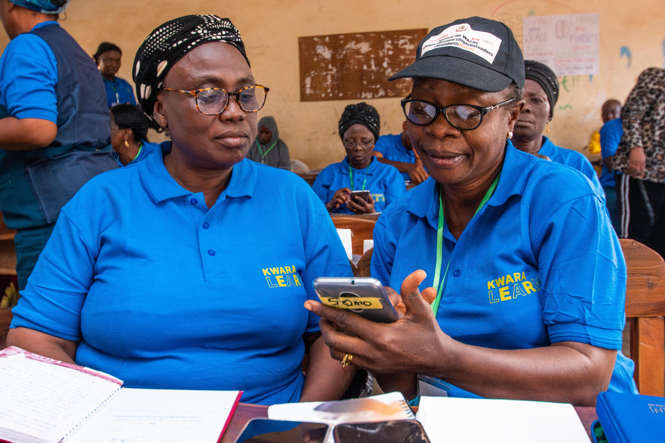 Two newly inducted KwaraLEARN headteachers showing each other around with the KwaraLEARN smart device.