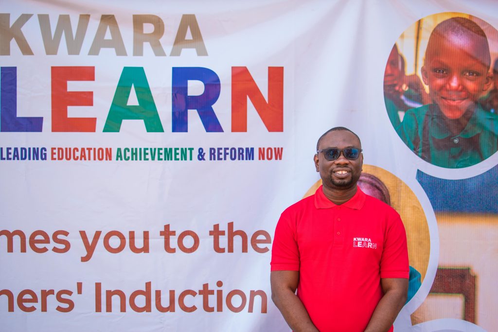 The Managing Director stands in front of a banner marking the successful completion of a teachers' induction training.