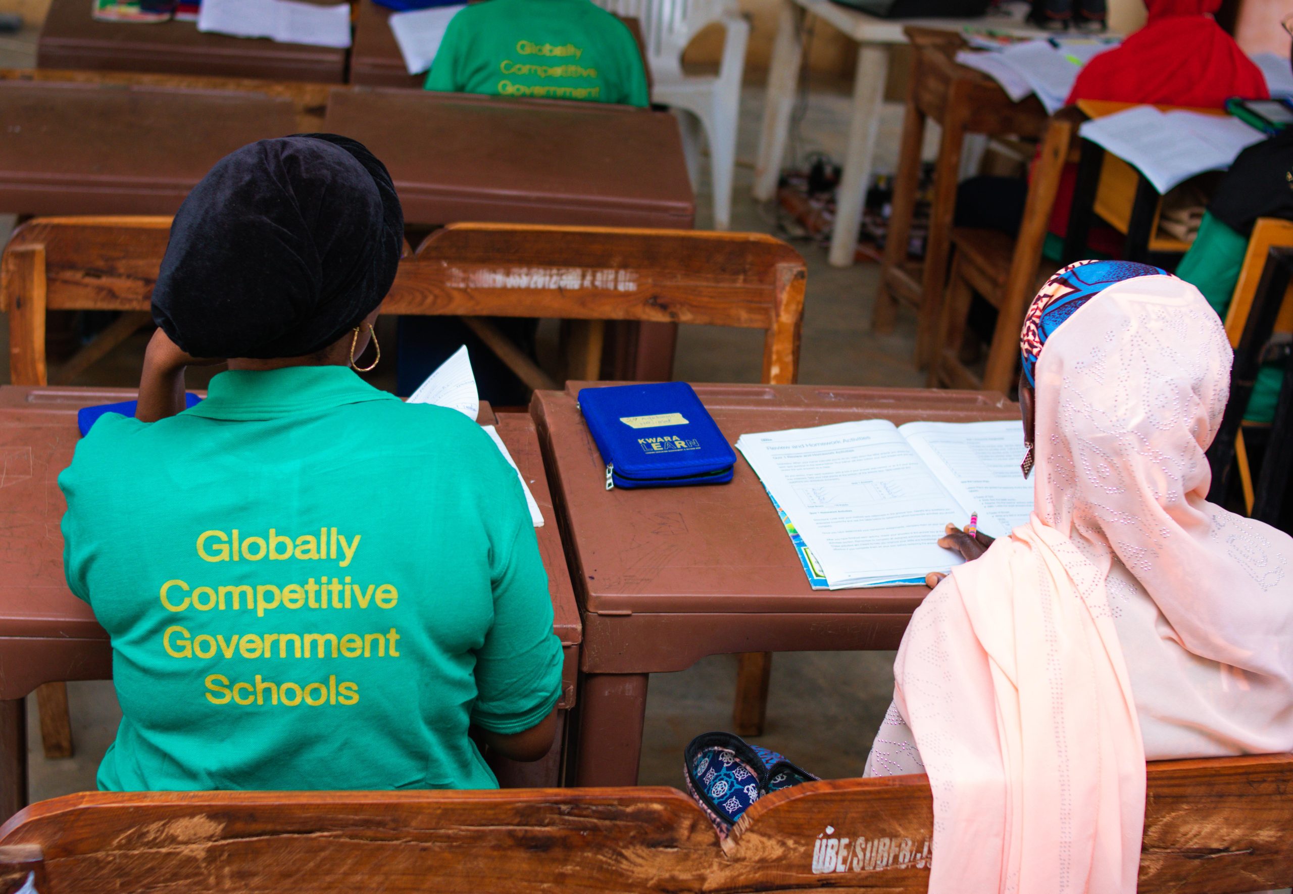 A KwaraLEARN Teacher in Green Shirt with 'Globally Competitive Government Schools' Inscription on thr back.